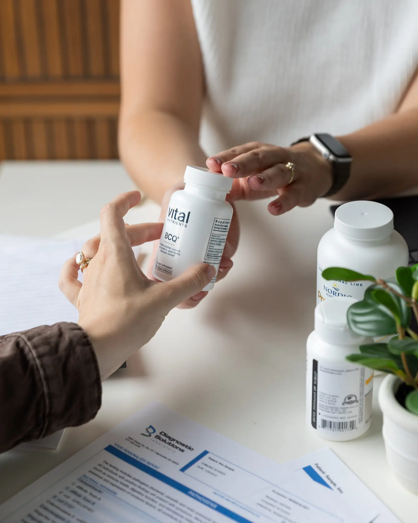 Dr. Abbie handing a patient a supplement bottle during a visit